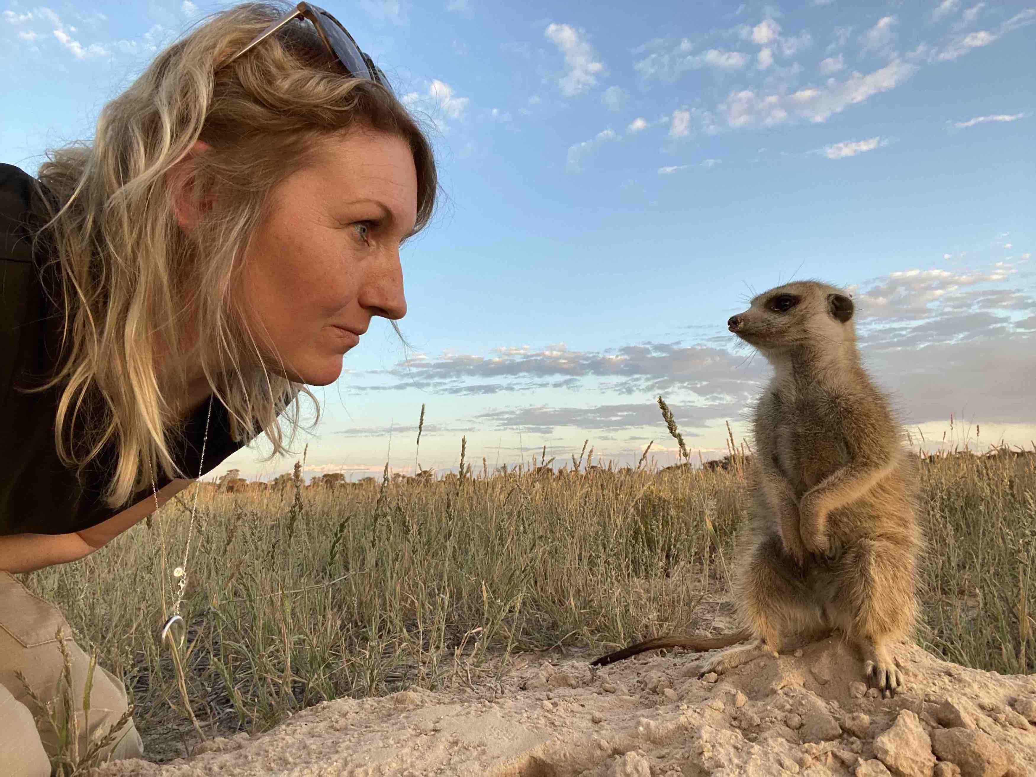 A photo of a woman and a meerkat