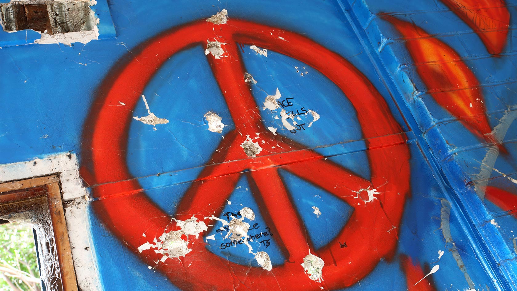 Peace-Symbol auf Haus mit Einschusslöchern