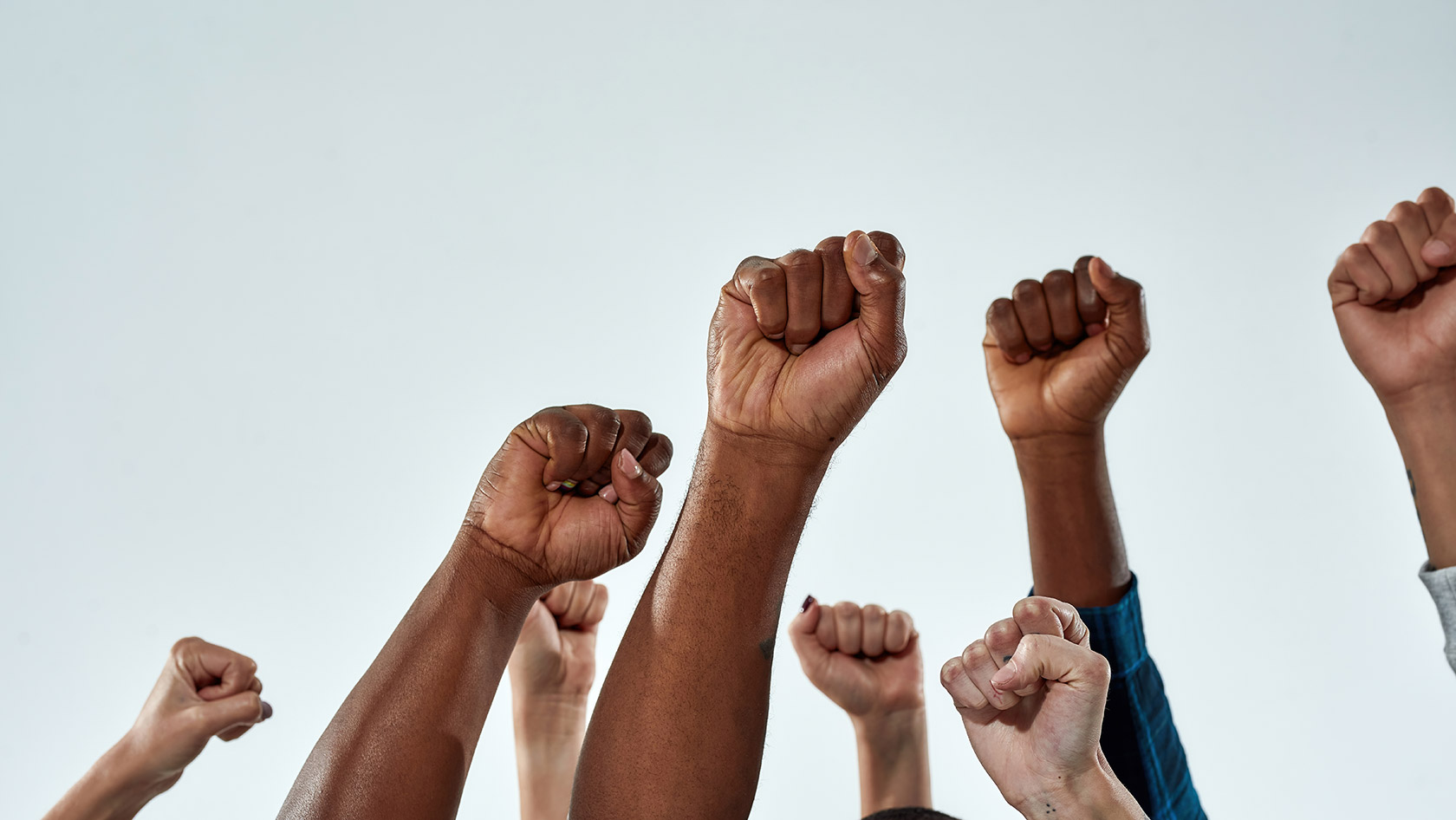 Raised hands of multiracial people clenched into fists