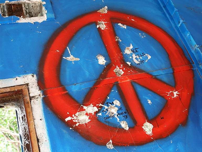 Peace-Symbol auf Haus mit Einschusslöchern
